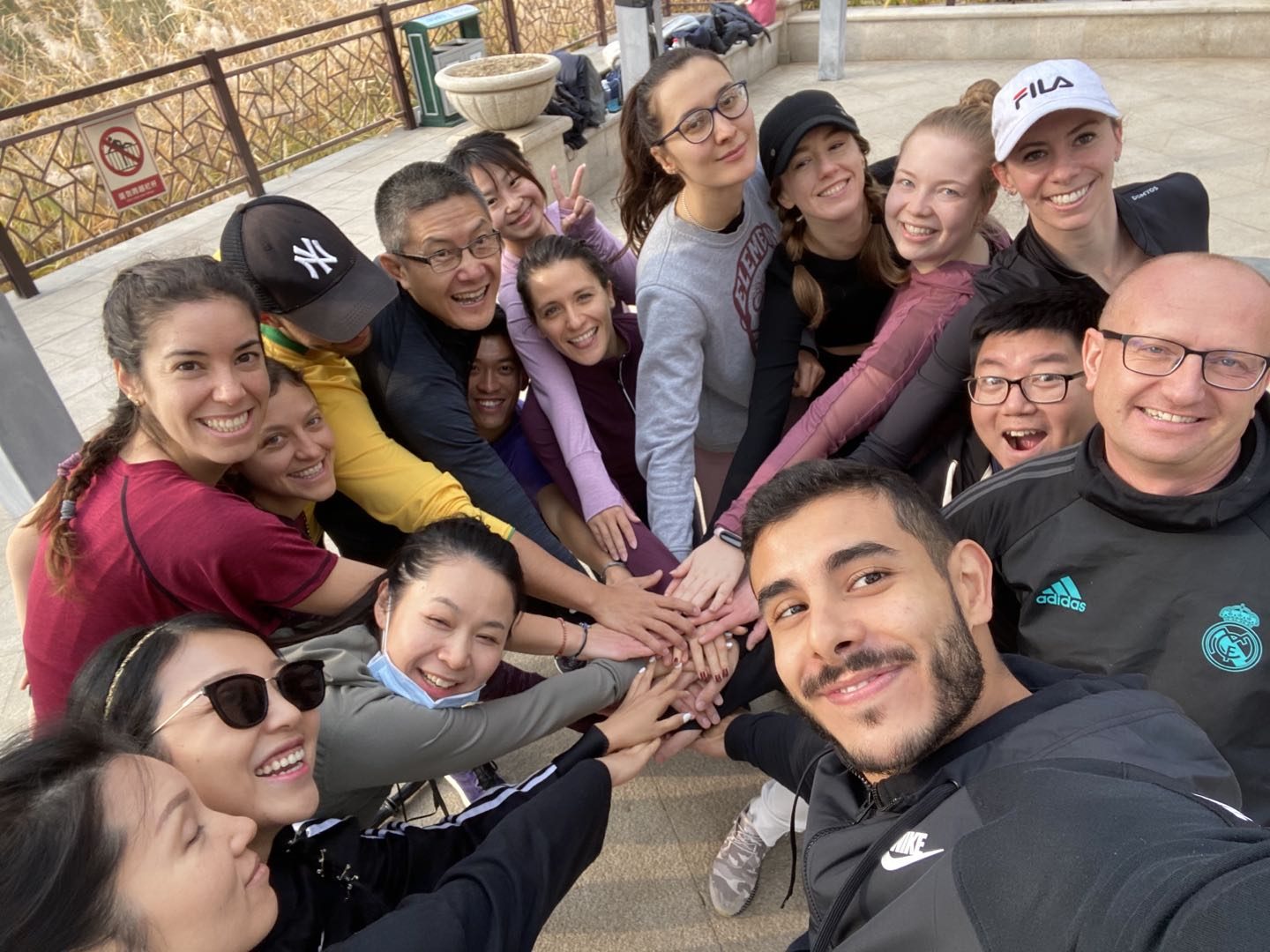 Angelo and a group of community members with their hands stacked together